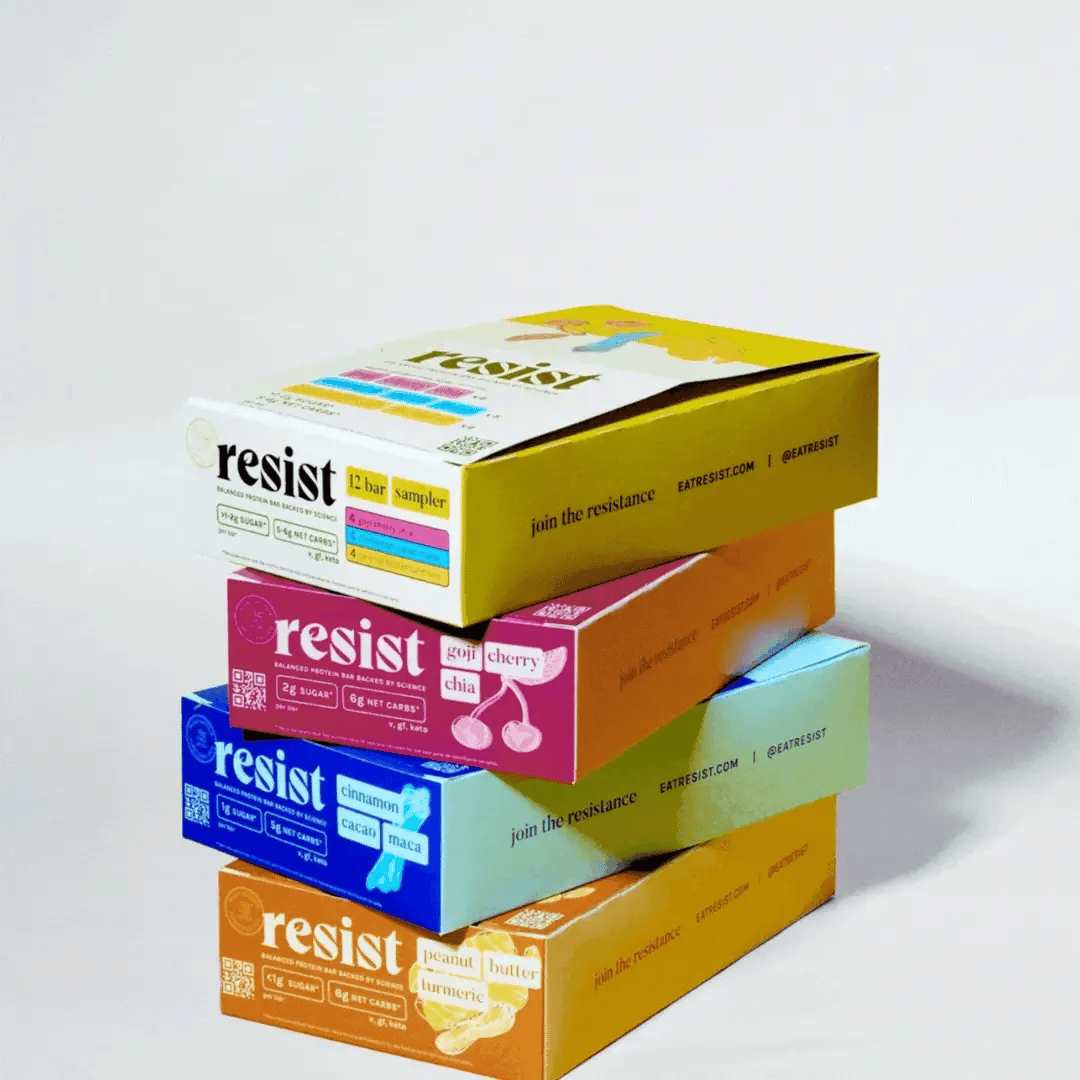 Stacked boxes of Resist bars in sampler, Goji Cherry Chia, Cinnamon Cacao Maca, and Peanut Butter Turmeric.